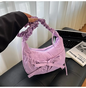 Close-up of a light purple pleated nylon shoulder bag with a stylish bow decoration