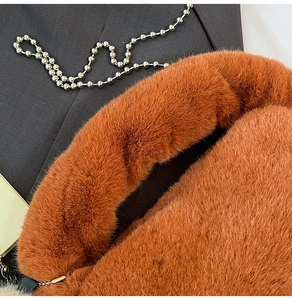Détail d'un sac à main en fausse fourrure orange avec une élégante bandoulière en chaîne