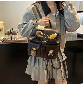 Detail of dark brown vintage faux leather backpack with plush bear and cookie charms