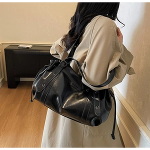 Detail of black large-capacity PU leather shoulder bag with drawstring and metal eyelets