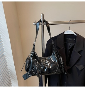 Détail d'un sac à bandoulière en cuir brillant style motard avec œillets et boucles en métal