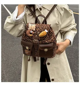 Detail of leopard print backpack with brown leather trim and cute plush pendants