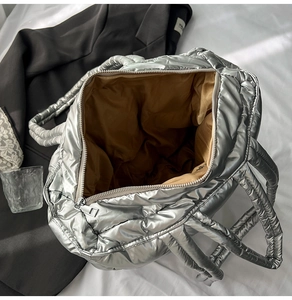 Detailed interior of silver quilted tote bag showing brown lining and metal zipper