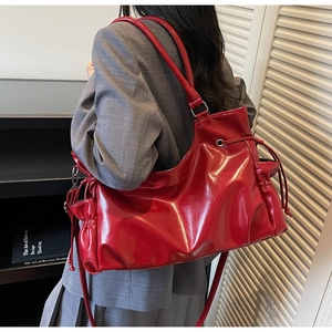 Detailed view of red glossy tote bag with drawstring sides shown on shoulder