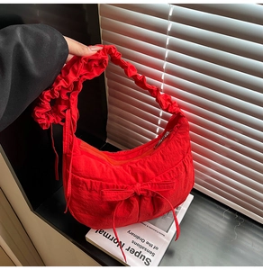 Detailed view of red nylon shoulder bag featuring ruffled straps and drawstring bow design