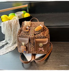 Detail of leopard print backpack with plush badges and faux leather flap in rustic setting