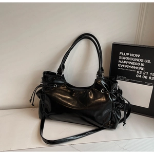 Detail of glossy black shoulder bag with side drawstring pleats and silver metal hardware