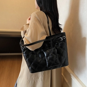 Sac cabas matelassé noir avec mini porte-monnaie porté sur un trench-coat beige chic