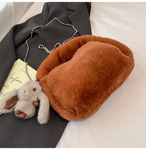 Détail d'un sac en peluche marron doux avec chaîne argentée et breloque lapin mignon