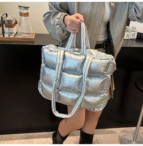 Close-up of metallic silver quilted tote bag showing square stitching and padded texture