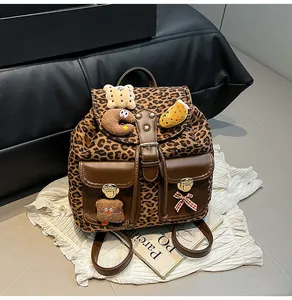Detail of leopard print backpack with plush bear charms and brown leather accents