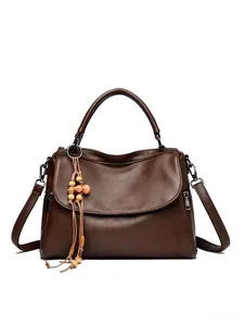 Detail of dark brown lychee texture leather tote bag with wooden bead tassel charm