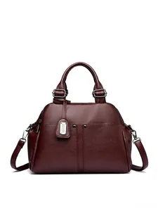 Detail of burgundy pebbled leather Boston bag with metal logo and detachable strap