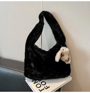 Detail of black faux fur shoulder bag with a cute grey plush rabbit pendant accessory
