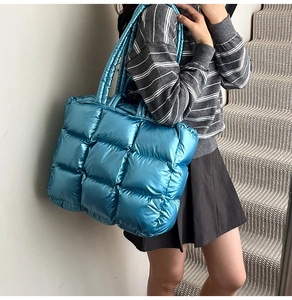 Detail of blue metallic quilted tote bag with large square stitching and padded handle