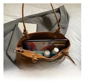 Vue de dessus montrant l'intérieur spacieux du sac en cuir marron avec objets du quotidien