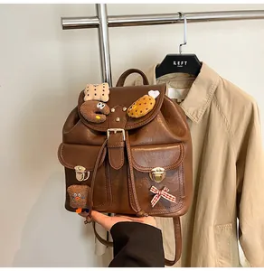 Close-up of vintage brown leather backpack with multiple pockets and cute plush charms
