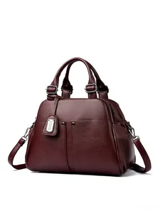 Macro shot of burgundy pebbled leather boston bag with detailed stitching and hardware