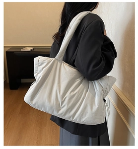 Detailed view of lightweight white quilted tote bag worn over the shoulder by a model