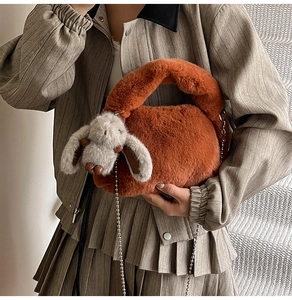 Close-up of caramel faux fur crossbody bag with chain strap and plush rabbit charm