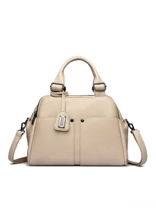 Macro detail of beige pebble grain leather texture and metallic hardware on Boston bag