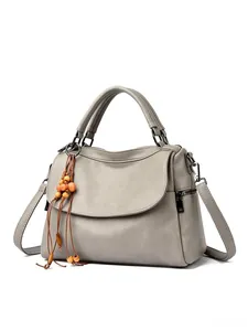 Close-up of grey leather handbag featuring detailed lychee texture and beaded tassel