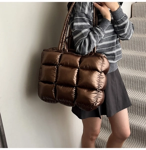 Macro detail of bronze puffer tote bag showing metallic quilted fabric and wide straps