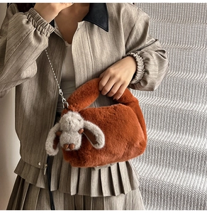 Close-up of fluffy orange-brown plush handbag with rabbit charm and gold chain strap