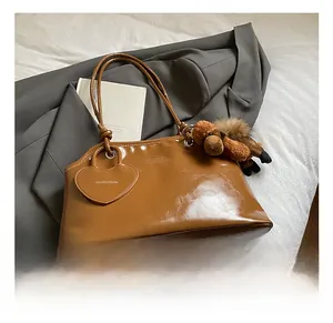 Détail du sac hobo en cuir ciré avec breloque cœur et peluche de chiot sur tissu gris