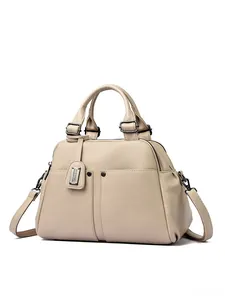 Detail of cream lychee texture leather Boston bag with metal tag and dual handles