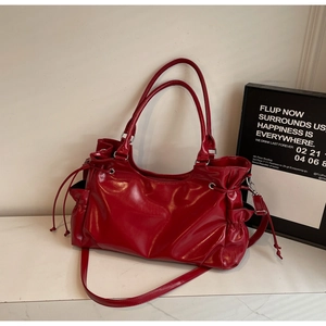 Close-up of red patent leather tote bag with functional side drawstrings and pockets