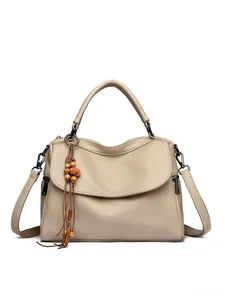 Close-up of beige tote bag with litchi grain leather and wooden bead tassel detail