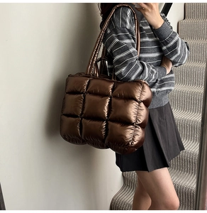Detailed macro view of bronze quilted tote bag with metallic puffer texture and stitching