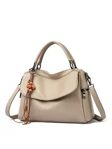 Close-up of beige lychee grain leather handbag featuring a wooden bead tassel charm