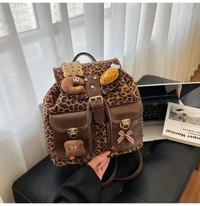 Detail of leopard print plush backpack with faux leather pockets and cute cartoon charms