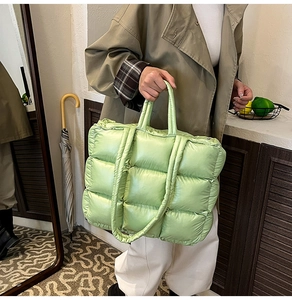 Close-up of light green quilted down tote bag showing puffy texture and large capacity
