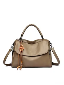 Detail of taupe pebbled leather tote featuring top handles and beaded tassel charm