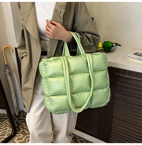 Detail of light green quilted nylon tote bag featuring oversized square puffer stitching