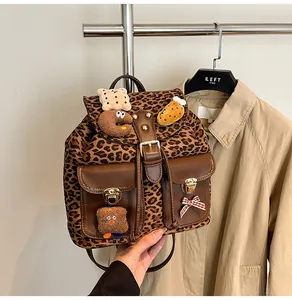 Detail of leopard print backpack with plush charms and golden twist-lock closures