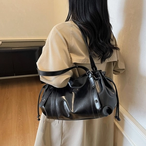 Sac à bandoulière noir en cuir ciré avec cordon de serrage porté par un mannequin