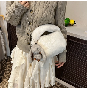 Détail de la texture peluche blanche avec charm de lapin gris et bandoulière en chaîne