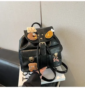 Close-up of black PU leather backpack with vintage buckles and cute plush biscuit charms