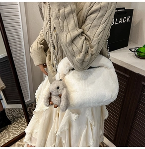 Gros plan sur un sac en peluche blanc avec chaîne argentée et breloque lapin doux