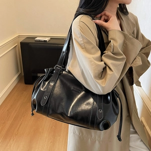 Sac fourre-tout noir brillant avec cordons latéraux et bandoulière réglable sur le mannequin