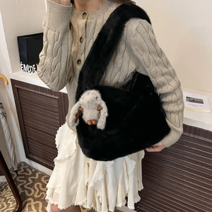Chic black plush shoulder bag with grey rabbit pendant on model in cream knit sweater