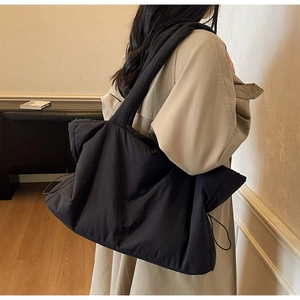 Détail du sac cabas matelassé noir avec cordon de serrage latéral et bandoulière large