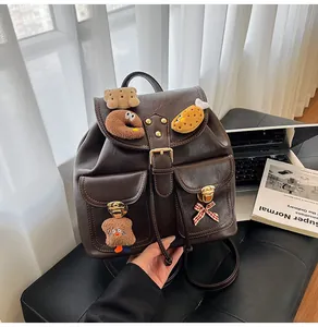 Close-up of vintage brown PU leather backpack with plush charms and gold metal locks
