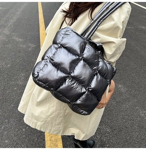 Quilted black down tote bag with spacious design worn over the shoulder outdoors