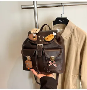 Detail of vintage brown leather backpack with cute plush charms and drawstring closure