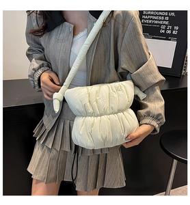Close-up of cream quilted cloud bag with pleated texture and stylish knotted strap design